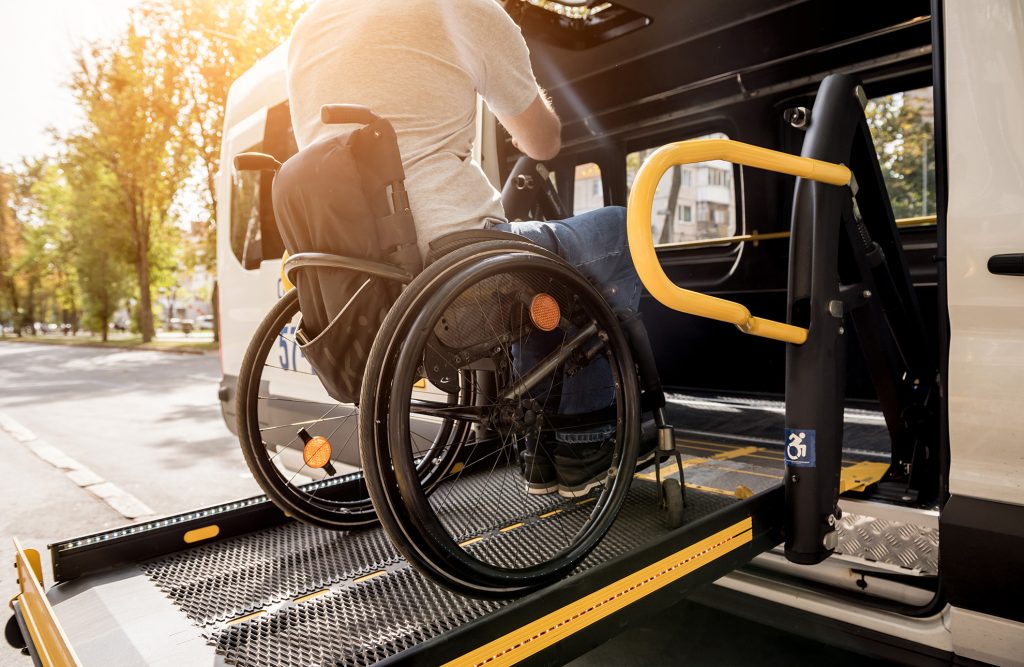 Das Bild zeigt wie ein Rollstuhl gerade in ein Fahrzeug geladen wird.